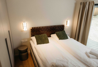 Moderne slaapkamer bij The Hills met Hottub, Wilsumer Berge, Duitsland, met twee bedden en groene kussens.