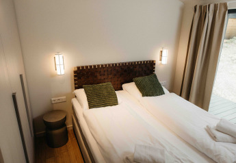 Moderne slaapkamer in The Hills met Hottub, Wilsumer Berge, Duitsland, met twee bedden en groene kussens.