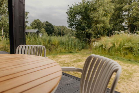 Uitzicht vanaf The Hills met Hottub-lodge bij Wilsumer Berge, Duitsland, met tafel, stoelen en natuur.