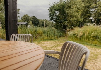 Zicht vanaf The Hills met Hottub-lodge bij Wilsumer Berge, Duitsland, met tafel, stoelen en natuur.