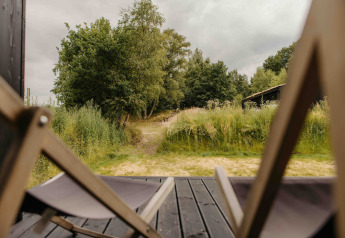 Zicht vanuit The Hills met Hottub, Wilsumer Berge, Duitsland, met ligstoelen en groene natuur buiten.