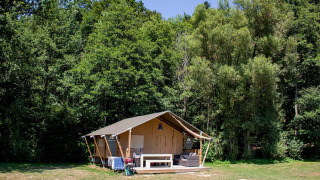 La tienda safari Villatent Wood en Camping Au Clos de La Chaume en Francia, rodeada de bosque verde.