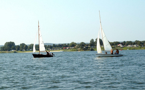 Twee zeilboten met mensen varen op het water bij vakantiepark Rhederlaagse Meren in Gelderland, Nederland.