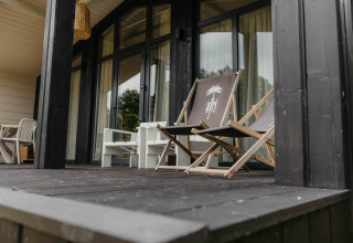 Veranda van The Hills met Hottub lodge in Wilsumer Berge, Duitsland, met loungestoelen en natuurrijke omgeving.