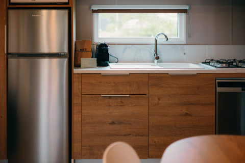 Cuisine aux Tiny Wander Lodges du Holiday Park Sallandshoeve aux Pays-Bas, avec placards en bois et électroménagers.