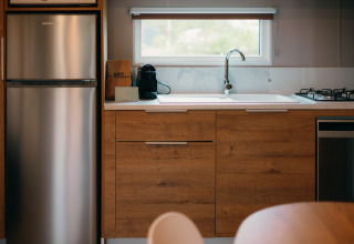Cuisine aux Tiny Wander Lodges du Holiday Park Sallandshoeve aux Pays-Bas, avec placards en bois et électroménagers.