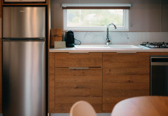 Cuisine aux Tiny Wander Lodges du Holiday Park Sallandshoeve aux Pays-Bas, avec placards en bois et électroménagers.