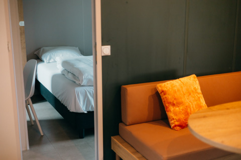 Chambre douillette aux Tiny Wander Lodges, Holiday Park Sallandshoeve avec lit, canapé et table.