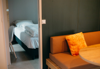 Chambre douillette aux Tiny Wander Lodges, Holiday Park Sallandshoeve avec lit, canapé et table.