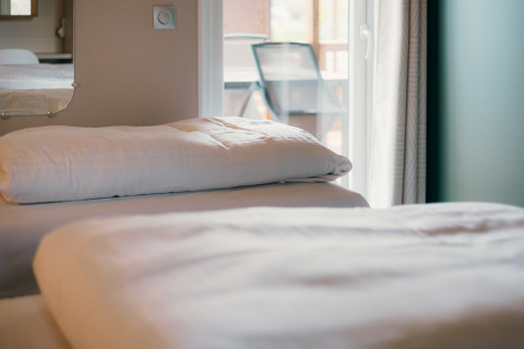 Gros plan sur un lit avec draps blancs aux Tiny Wander Lodges, Holiday Park Sallandshoeve, Pays-Bas.