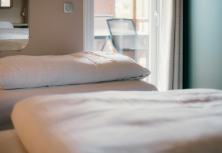 Gros plan sur un lit avec draps blancs aux Tiny Wander Lodges, Holiday Park Sallandshoeve, Pays-Bas.