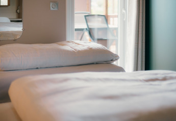 Gros plan sur un lit avec draps blancs aux Tiny Wander Lodges, Holiday Park Sallandshoeve, Pays-Bas.
