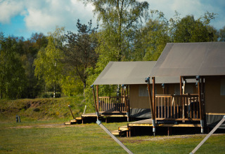 Safari tents at Wilsumer Berge in Germany, surrounded by greenery and trees on a bright sunny day.