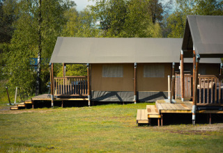 Safari tent at Wilsumer Berge in Germany, surrounded by trees and grassy open space in the foreground.