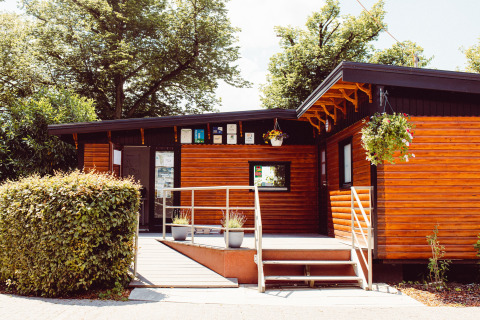 Wooden cabin at Camping Liefrange holiday park in Wiltz, Luxembourg, decorated with plants and flowers.
