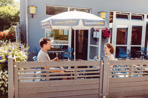 Due persone si godono un gelato sotto un ombrellone al Camping Liefrange, parco vacanze a Wiltz, Lussemburgo.
