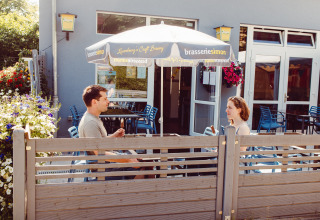 Due persone si godono un gelato sotto un ombrellone al Camping Liefrange, parco vacanze a Wiltz, Lussemburgo.