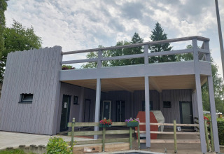 Casetta moderna con terrazza in legno al Camping Liefrange a Wiltz, Lussemburgo, sotto un cielo nuvoloso.