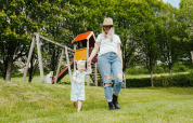 Mother and child playing on green grass near playground with slide at Camping Liefrange, Wiltz, Luxembourg.