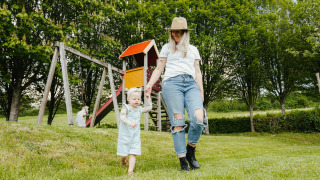 Mutter und Kind spielen auf der Wiese bei Spielplatz und Rutsche im Camping Liefrange, Wiltz, Luxemburg.