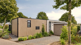 Lodge moderne Module Special 4 personnes, bardage bois, grande allée et espaces verts à l’avant.