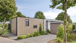 Lodge moderne Module Special 4 personnes, bardage bois, grande allée et espaces verts à l’avant.