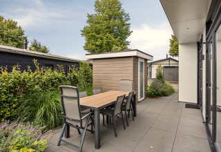 Terrasse extérieure avec table et six chaises près du lodge Module Special 4 au Recreatiepark het Esmeer.