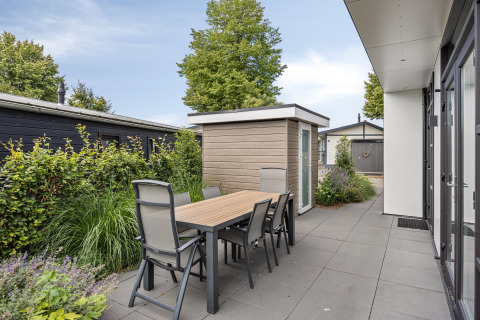 Terras met tafel en zes stoelen bij de Module Special 4 lodge in Recreatiepark het Esmeer, Nederland.