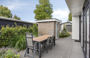 Terras met tafel en zes stoelen bij de Module Special 4 lodge in Recreatiepark het Esmeer, Nederland.