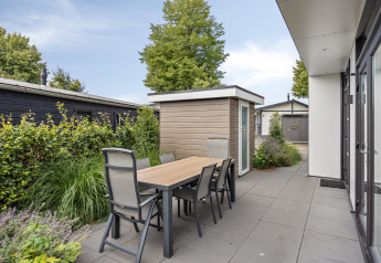 Patio esterno con tavolo e sei sedie presso il lodge Module Special 4, Recreatiepark het Esmeer, Paesi Bassi.