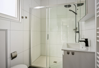 Modern bathroom with shower, white tiles, black faucet and a window in Module Special 4 personen lodge.