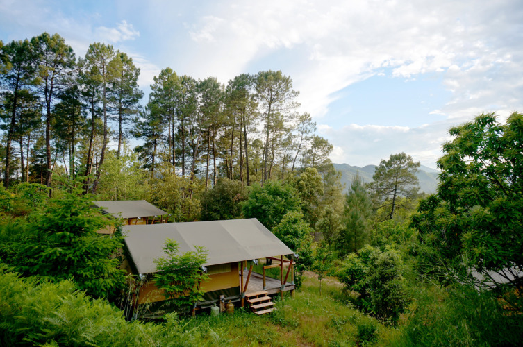 Das Safari-Zelt Baroudeur Tent bei Bivouac nature in Frankreich, umgeben von Wald und Bergen bei klarem Himmel