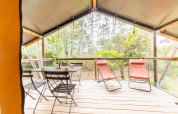Vista dalla tenda safari Baroudeur al Bivouac nature in Francia, con tavolo, sedie e sdraio nel verde