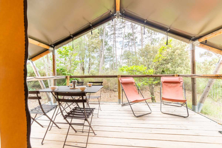 Uitzicht vanuit de Baroudeur-safaritent bij Bivouac nature in Frankrijk met tafel, stoelen en ligstoelen