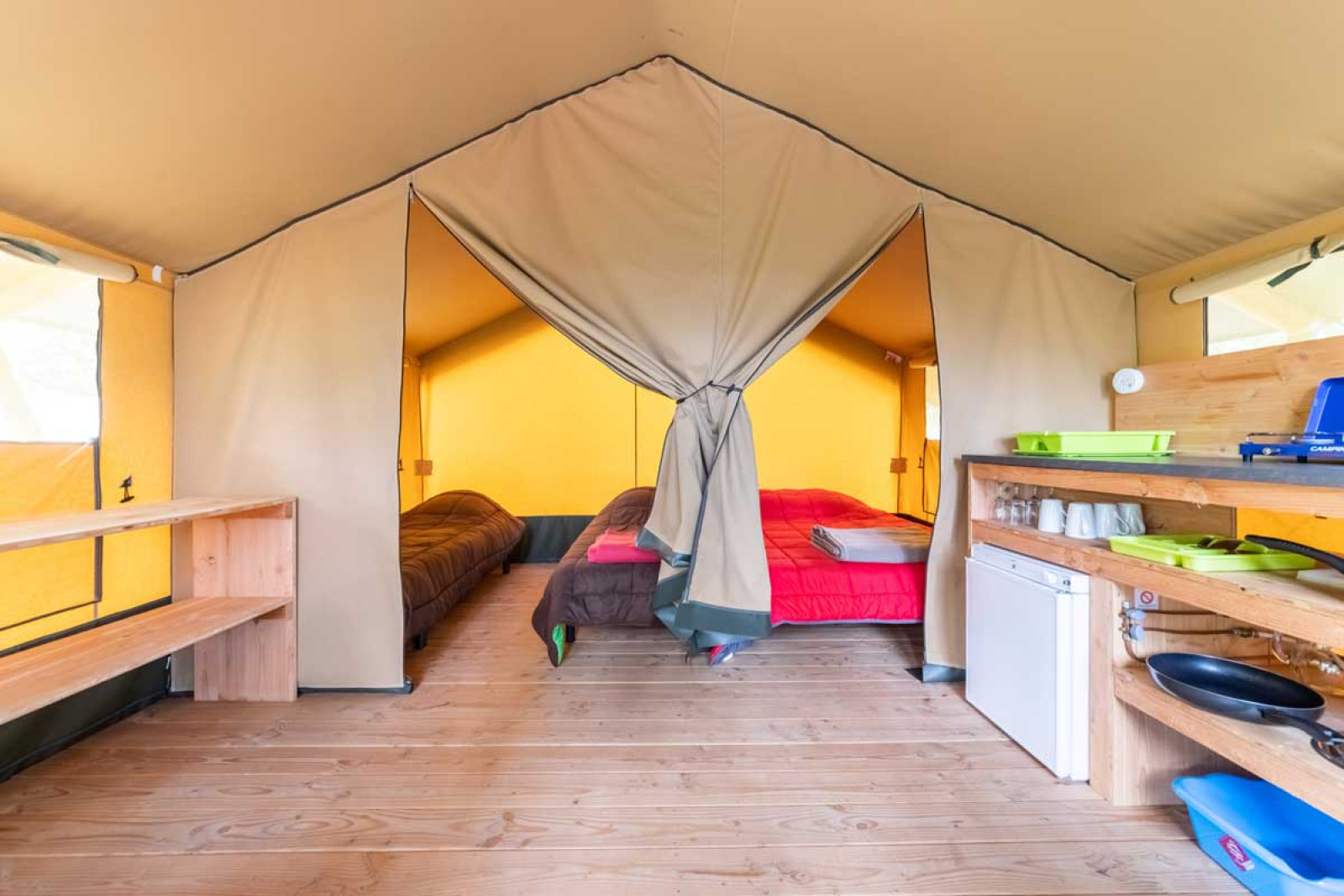 Binnenaanzicht van de safari Baroudeur tent bij Bivouac nature in Frankrijk, met bedden en keukenhoek.