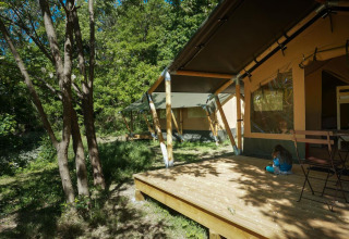 Safari-Zelt Baroudeur Tent bei Bivouac nature in Frankreich mit Kind auf der Holzterrasse im Wald.