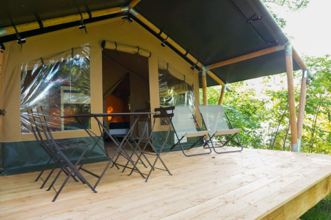 Terraza de madera con mesa y sillas frente a la tienda safari Baroudeur en Bivouac nature, Francia.