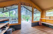 Interno della tenda Baroudeur al Bivouac nature in Francia, con terrazza in legno e vista sulla natura.