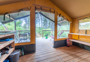 Interior de una tienda Baroudeur en Bivouac nature, Francia, con terraza de madera y vistas a la naturaleza.