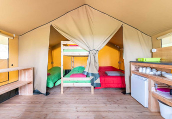 Interior de la tienda Baroudeur en Bivouac Nature, Francia, con literas, cama doble y cocina básica.