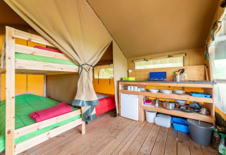 Intérieur de la tente safari Baroudeur avec lits superposés et cuisine à Bivouac Nature, France.