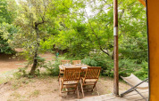 Outdoor wooden dining set beside the Canadienne Tent at Bivouac nature in France, surrounded by trees.