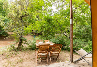 Outdoor wooden dining set beside the Canadienne Tent at Bivouac nature in France, surrounded by trees.