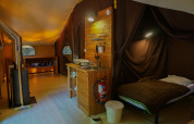 Interno di una tenda safari Canadienne con stufa a legna, letto e angolo cottura presso Bivouac nature in Francia.