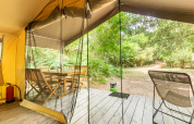 Vista dalla tenda safari a Bivouac nature, Francia, con terrazza in legno, tavolo, sedie e verde naturale.