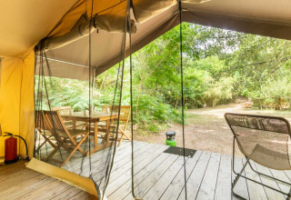 Vista dalla tenda safari a Bivouac nature, Francia, con terrazza in legno, tavolo, sedie e verde naturale.