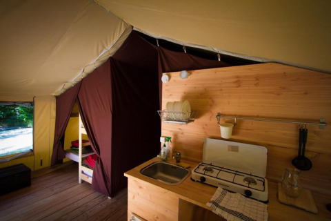 Interieur van een safaritent met keuken en stapelbed bij Bivouac nature in Frankrijk.