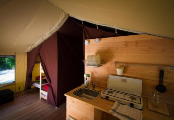 Interno di una tenda safari con cucina e letto a castello presso Bivouac nature in Francia.