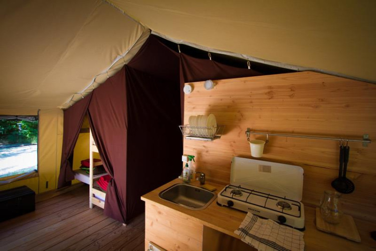 Interno di una tenda safari con cucina e letto a castello presso Bivouac nature in Francia.