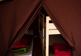 Interno della Safari Tent al Bivouac nature in Francia con pavimento in legno, letti e coperte.